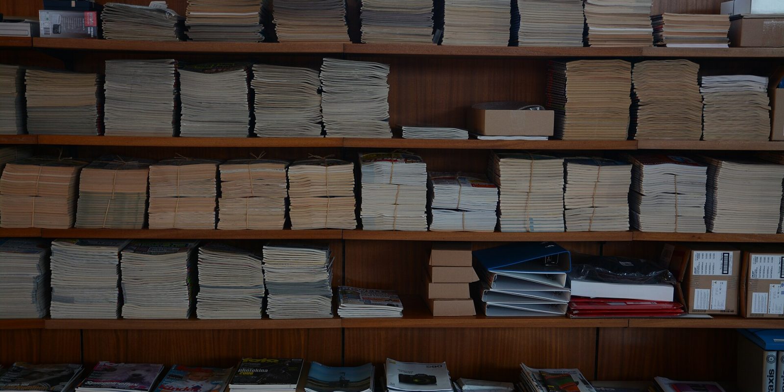 Shelves holding many neat stacks of photography and computer magazines