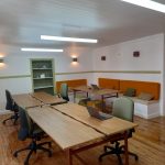Modern coworking office with shared wooden desks, chairs and soft lighting