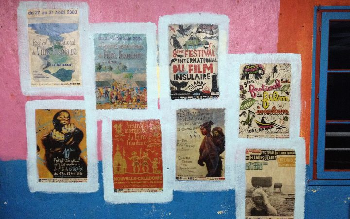 Colourful festival posters pasted on a brightly painted pink and blue wall