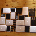 Laptops, tablets and smartphones laid out in a grid on a wooden floor