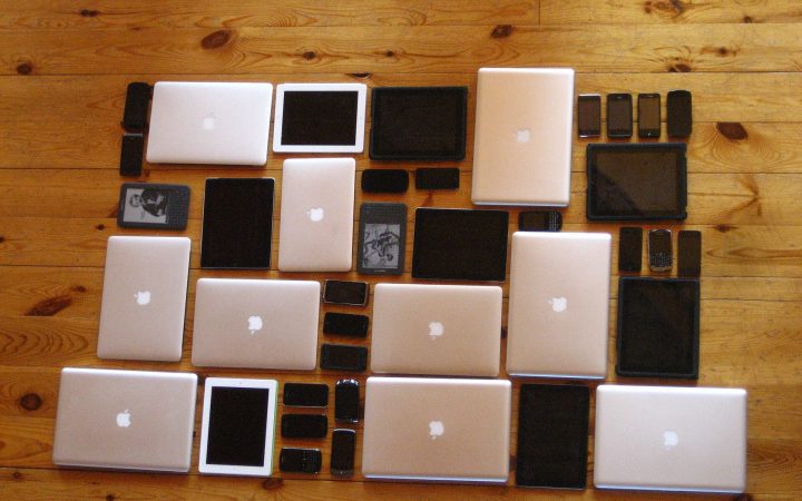 Laptops, tablets and smartphones laid out in a grid on a wooden floor