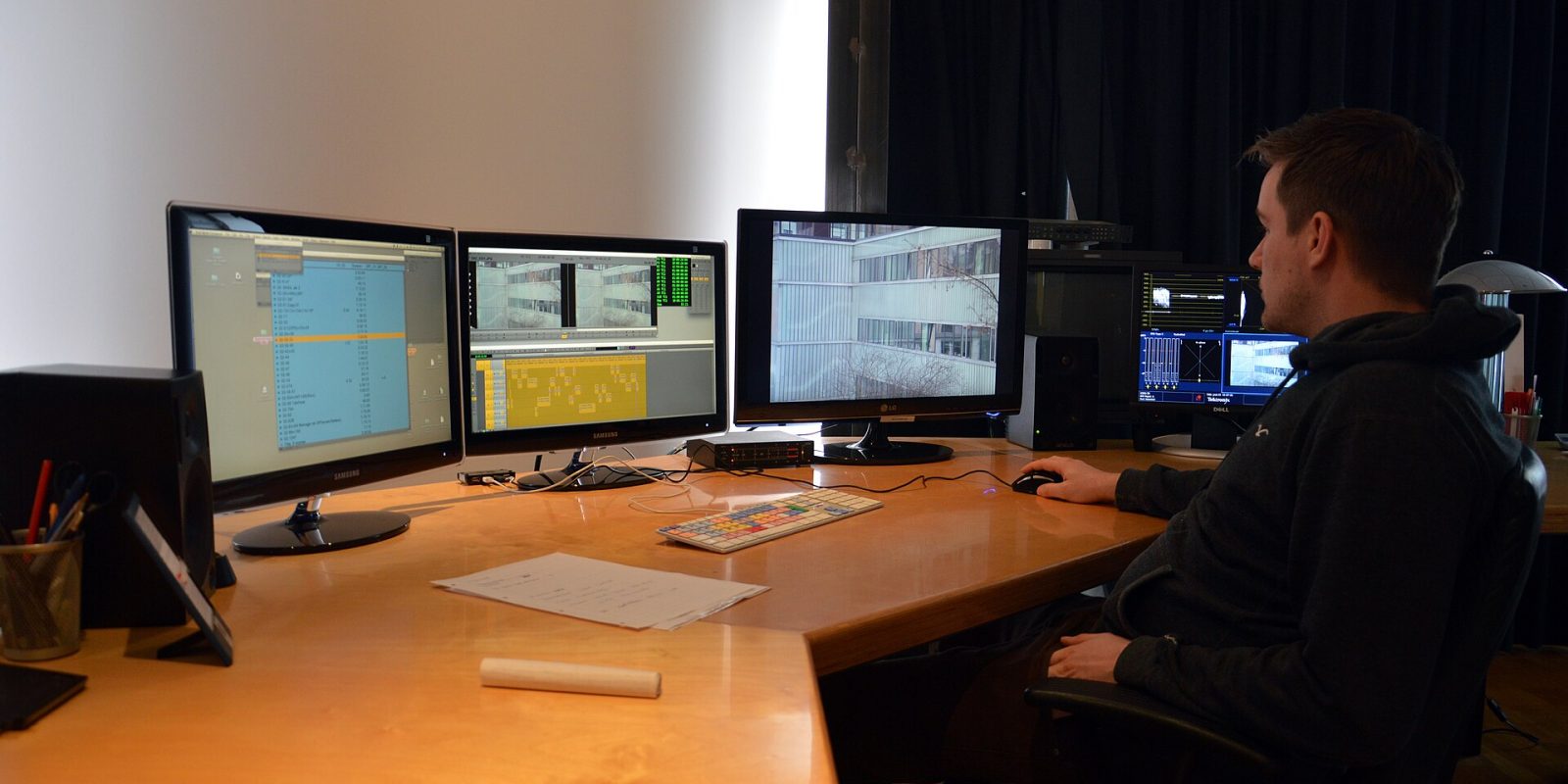 Editor at a digital editing suite with several monitors showing video editing software