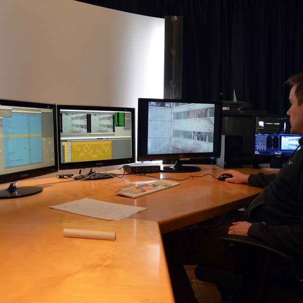 Editor at a digital editing suite with several monitors showing video editing software